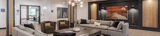 A modern living room with a grey sofa set and a large abstract painting on the wall.