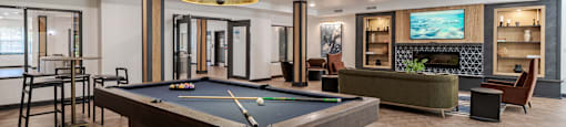 A pool table is in the middle of a room with a fireplace and a TV.