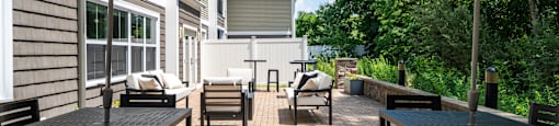 A patio with tables and chairs under striped umbrellas.