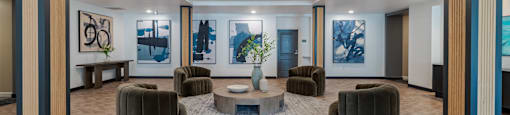 A spacious room with a central table surrounded by chairs and framed pictures on the walls.