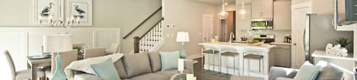 A living room with a grey couch and a glass coffee table.