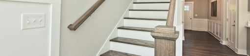 A staircase with wooden steps and a dark brown handrail.