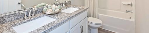 A bathroom with a granite countertop and a white toilet.