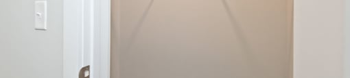 Empty white closet with a white door and a white light switch.