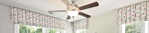 A bedroom with a bed, dresser, and a ceiling fan.