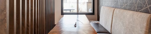 A long wooden table with a couch and a window in the background.