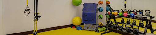 A gym room with a yellow floor and a variety of exercise equipment.