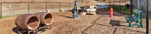 Ashland Farms Community Fenced-In Bark Park with Seating, Play Barrels, and Shade.