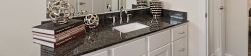 Ashland Farms Bathroom Vanity with Spacious Granite Counters, Large Mirror, and Modern Light Fixtures