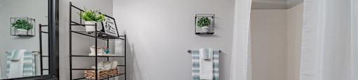 Bathroom vanity with framed mirror hung above. Toilet to the right. Tub/Shower can be seen in mirror reflection.