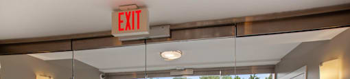 a door leading to a courtyard with a gate and a exit sign