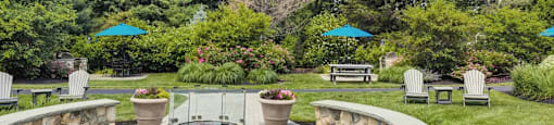 a patio with a fire pit and benches in a garden