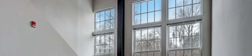 an empty room with three windows and a carpeted floor