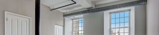 an empty living room with two windows and a door