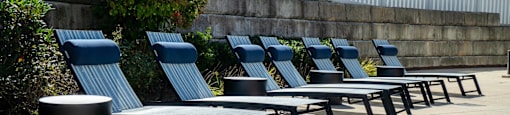 a row of lounge chairs and tables next to a pool