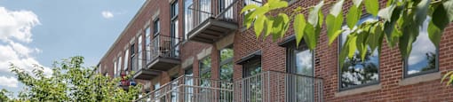 A red brick building with a balcony and a wooden fence.