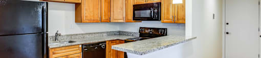 Kitchen with natural colored cabinets and black appliances