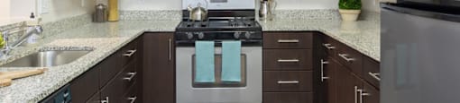 A kitchen with dark brown cabinets and a stainless steel refrigerator.