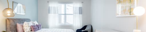 A bedroom with a bed, chair, and a desk.
