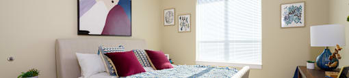 A bedroom with a bed, a nightstand, and a painting on the wall.