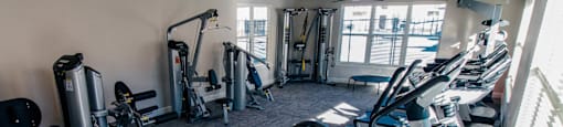 A gym with a variety of exercise equipment including treadmills, stationary bikes, and weight machines.