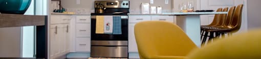 A modern kitchen with a yellow chair in the foreground.