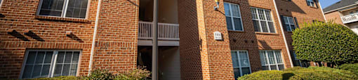 A brick building with a hedge in front and a lamp post to the left.