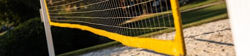 A yellow soccer goal stands on a sandy field.