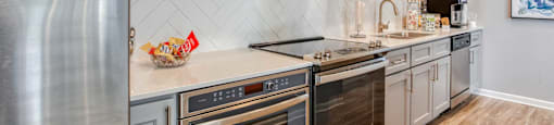 A modern kitchen with stainless steel appliances and wooden shelves.
