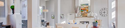 A modern kitchen with white chairs and a bar counter.