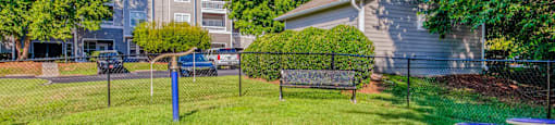A grassy area with a bench and a fence in front of a building.
