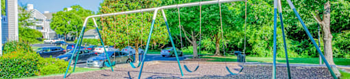 A playground with a swing set in the middle of a gravel area.