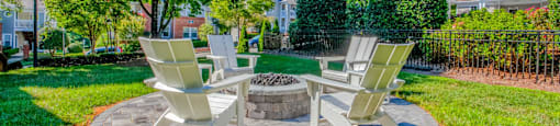 Two chairs are placed around a fire pit in a grassy area.