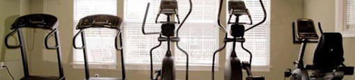 A room with a treadmill, elliptical trainer, and two stationary bikes.
