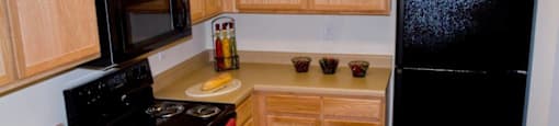 A kitchen with wooden cabinets and a black refrigerator.