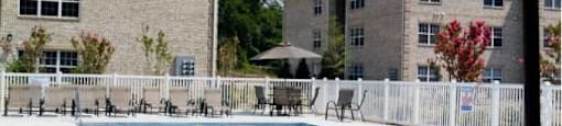 A table and chair set up under an umbrella by a pool.
