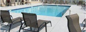 A pool surrounded by chairs in front of a house.