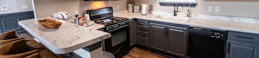 A kitchen with dark wood cabinets and a marble island.