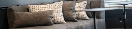 A grey couch with four pillows on it.