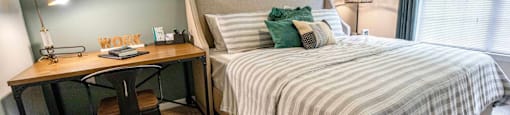 A bedroom with a bed, desk, and chair.