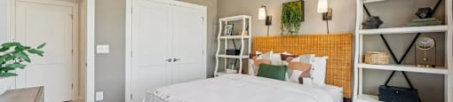 A bedroom with a white bed and a yellow accent wall.