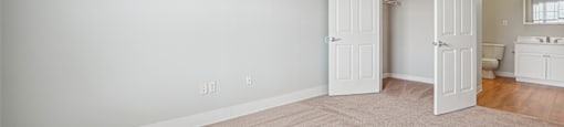 A room with a carpeted floor and a doorway leading to another room.