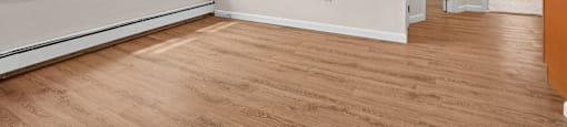 A room with wooden floors and a window with blinds.