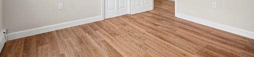 A room with a white door and a wooden floor.