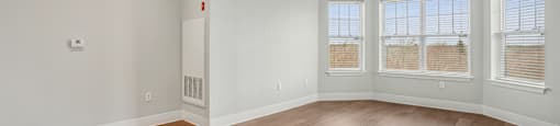 A large empty room with wooden floors and white walls.