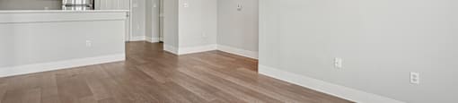 A spacious room with wooden flooring and white walls.