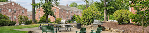 A green park area with a table and chairs in front of a building.