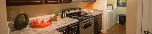A kitchen with brown cabinets and a granite counter top.