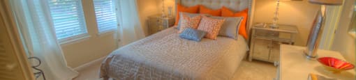 A bedroom with a large bed and a window with curtains.