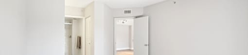 A room with white walls and wooden flooring with a door on the right.